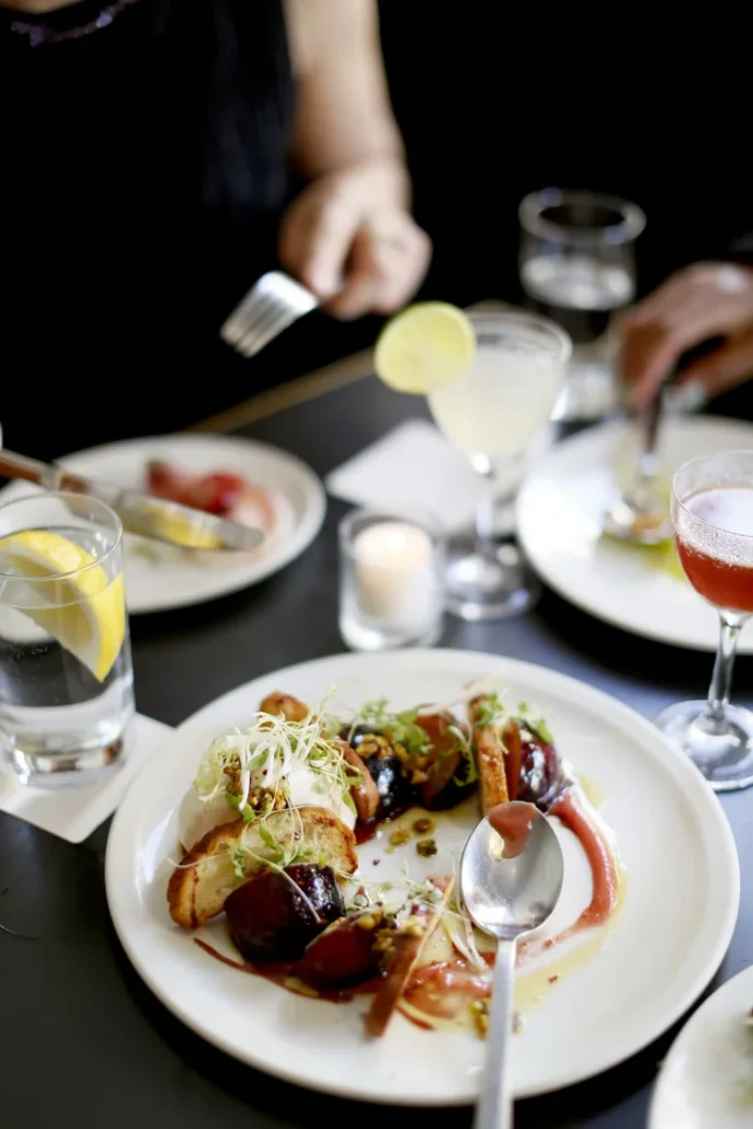 white plates on a dark table top filled with colorful artistic food