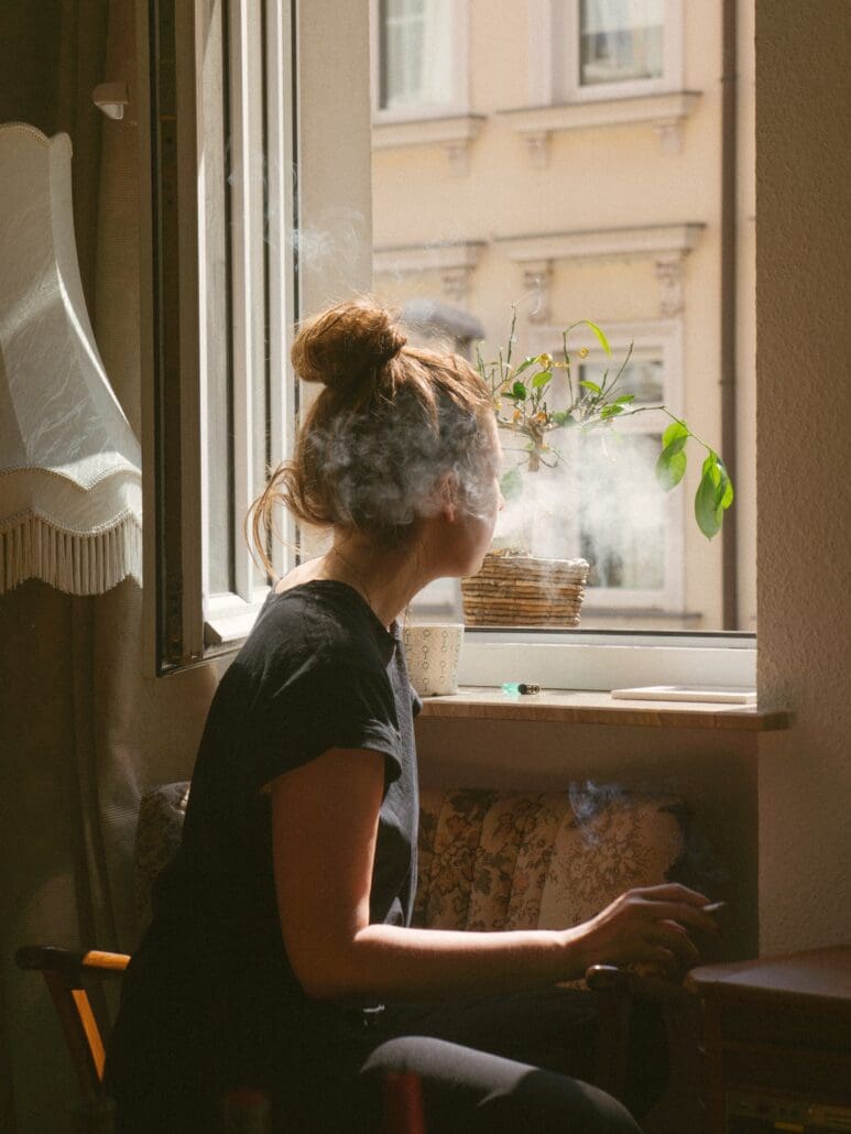 woman smoking weed in Seattle while look through the window