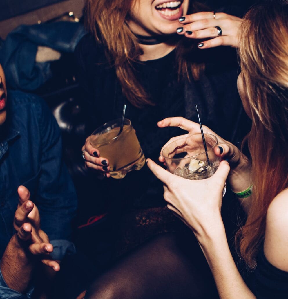 two women talking while holding drinking glasses and crossfading