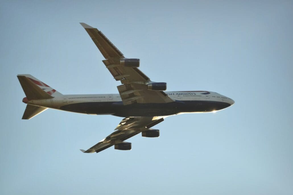 flying grey and blue plane during daytime against a cloudless light blue sky